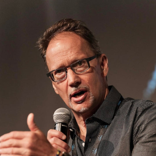 Man speaking into a microphone with a blurred background